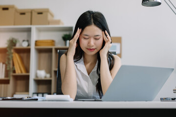 Young sad businesswoman is sitting at table, covering his face, under stress from working.