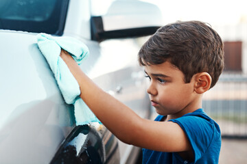 Child, car and cleaning with cloth outdoor for youth responsibility or discipline, chores or shining. Boy, vehicle and polish activity for household to do list for helping task, service or learning