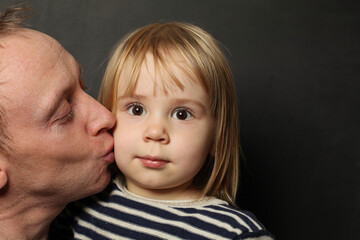 Portrait of smiling father and little daughter hugging and kissing. Happy young dad and cute adorable girl  enjoying leisure time together