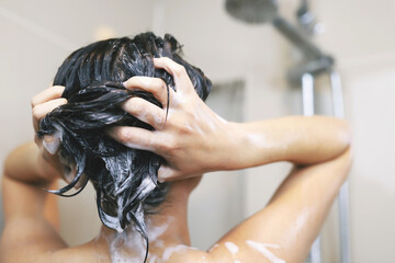Naklejka premium Woman is washing her hair with shampoo.
