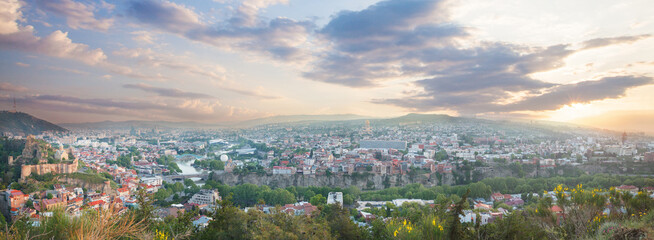 Panoramic beautiful landscape of historical Tbilisi with mountains and blue cloudy sky on the background