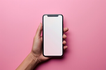 Woman's hand holding mobile phone with white empty screen in front of pink background with copy space.