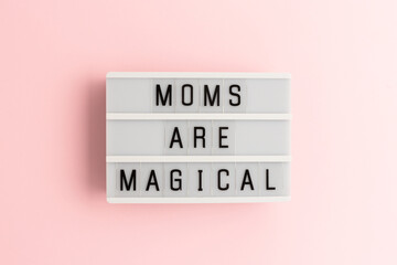 Moms are magical. White lightbox with letters on a pink background.