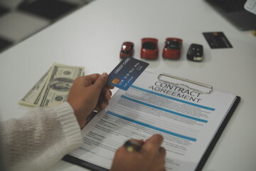 auto business, sale and people concept - close up of customer giving credit card to car dealer in...