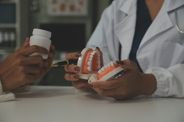 Concentrated dentist sitting at table with jaw samples tooth model and working with tablet and...