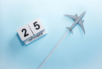 October calendar with number  25. Top view of a calendar with a flying passenger plane. Scheduler. Travel concept. Copy space.