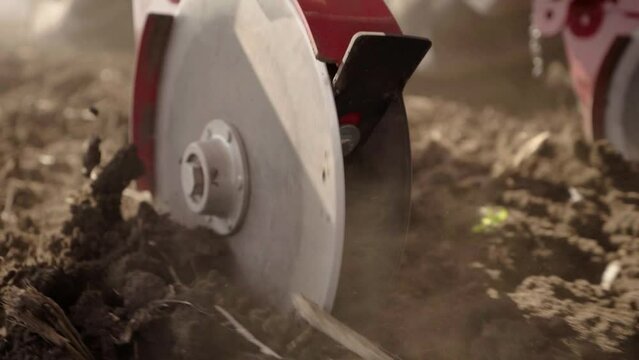 Close up of the seeder wheel that puts fertilizer in the ground in slow motion