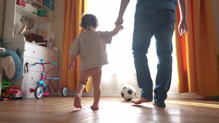 baby first steps with dad. happy family a kid dream concept. dad and baby daughter walk along the corridor of the house indoors. dad and daughter care, hold hands, walk, lifestyle take first steps