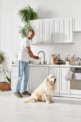 An African American man with myasthenia gravis stands next to his Labrador dog in a cozy kitchen,...