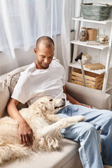 A man with myasthenia gravis relaxing on a couch with his Labrador dog, showcasing diversity and inclusion.