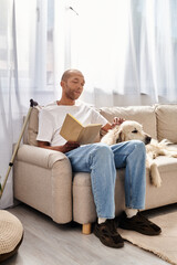 An African American man with myasthenia gravis sitting on a couch with his Labrador dog, showcasing diversity and inclusion.