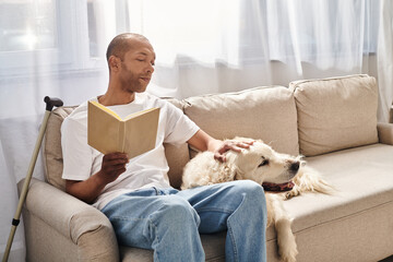 A disabled African American man with myasthenia gravis reading a book on a couch next to his loyal...