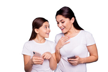 Fototapeta premium Close up photo beautiful two people brown haired mom small little daughter shows telephone look wondered great news can not believe own eyes wear white t-shirts isolated bright blue background