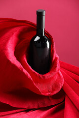 Stylish presentation of delicious red wine in bottle on pink background