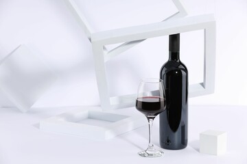 Stylish presentation of delicious red wine in bottle and glass on white background. Space for text