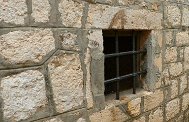 Window opening of a stone house covered with a metal grill