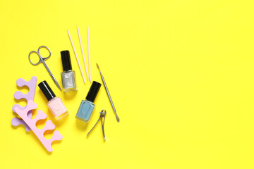 Nail polishes and set of pedicure tools on yellow background, flat lay. Space for text - obrazy, fototapety, plakaty