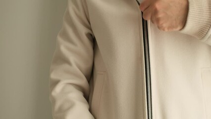 man zipping up white coat