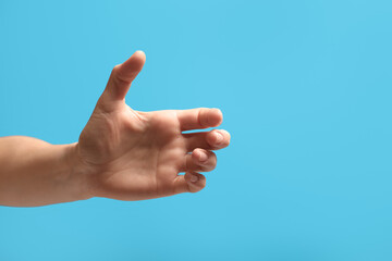 Woman holding something in hand on light blue background, closeup. Space for text