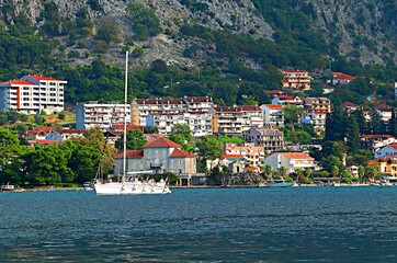 Pleasure yacht in the Bay of Kotor against the backdrop of the resort village and mountains
