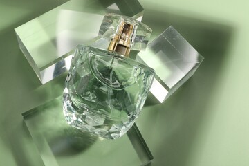 Stylish presentation of luxury perfume in sunlight on olive background, above view