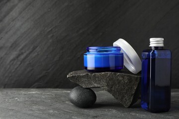 Cosmetic products and stones on grey background. Space for text