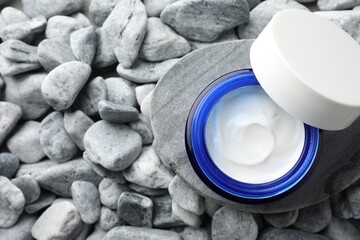 Jar of moisturizing cream on stones, top view. Space for text