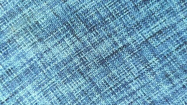 Stop motion loop animation footage of moving blue color cotton denim cloth sheet surface background texture with copy space. Textile industry and fashion business concept. Closeup macro top view.