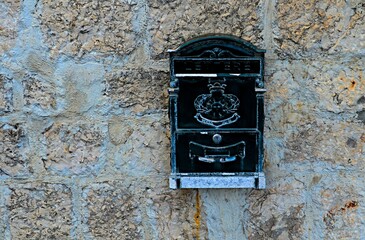 Black metal mailbox on a stone wall at home