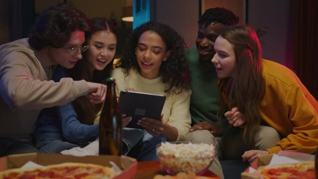 Brunette female holding digital tablet surrounded with friends