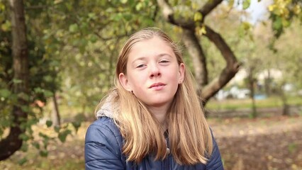 Portrait preteen girl on the fall nature background. Girl 15 years old. Blonde long hair. Forest, woods. Attractive teenager. Smiling teen girl.
