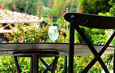 Wine glass on a table in a garden with flowering plants

