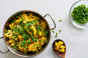 Freshly homemade spicy green pea and cauliflower curry, garnished with coriander in a wok, isolated...