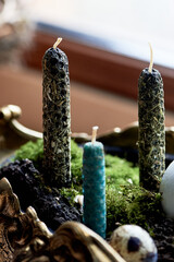 A green bowl filled with candles and moss sits on a wooden window sill, surrounded by terrestrial plants and grass. A twig and rope add to the natural houseplant landscape - 786188698