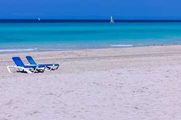 The beautiful beach front of the Cuban town of Varadero in Cuba showing two sun loungers on the...