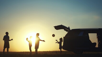 family traveling by car. family watching the sunset silhouette next to the car in the park. family playing ball. people in the park lifestyle. family car camping resting in nature