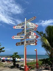 Signpost with various directions on a sandy Padang Beach, Indonesia