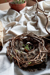 A bird nest made of twigs, grass, and natural materials, with a broken egg inside. The nest is built on the ground using soil, wood, and terrestrial plants - 786192882
