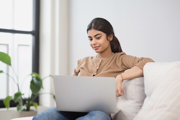 Young woman using laptop computer at home. Student girl working in her room. Work or study from home, freelance, casual business, lifestyle concept