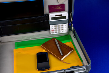 Briefcase with Notebook Pen Mobile Phone Calculator and Files on a Blue Surface - 786196483