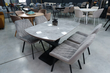 Gray wooden table complete with gray wooden chairs with soft fabric upholstery. Black glass jar with incense sticks on the table