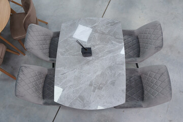 Gray wooden table complete with gray wooden chairs with soft fabric upholstery. Black glass jar with incense sticks on the table