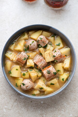 Dublin coddle served in a grey plate, vertical shot on a beige stone background, high angle view