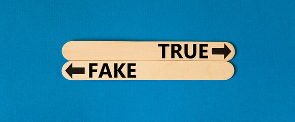True or fake symbol. Concept word True or Fake on beautiful wooden stick. Beautiful blue table blue...