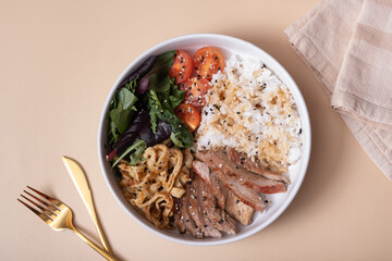Bowl with rice, veal and vegetables and cutlery top view. Balanced nutrition concept