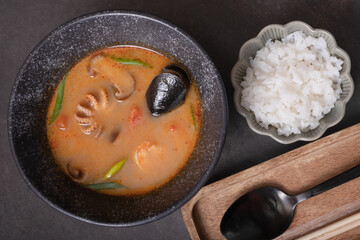 Tom yum soup with seafood and rice ondark background top view