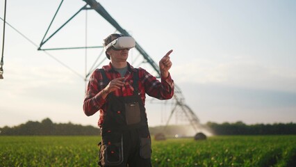 agriculture virtual reality. a farmer in virtual reality glasses controls a machine to irrigate corn field. agriculture virtual reality concept. a farmer vr in business works in field with corn