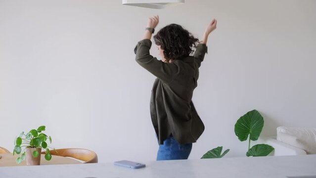 joyful young woman dancing at home having fun celebrating with playful dance moves enjoying freedom on weekend morning. Female have a nice day