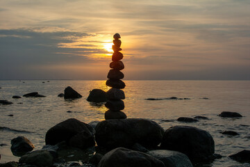 Stacked stones on a coast at orange sunset