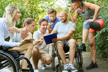 Inclusive group of friends sharing a laugh in a park, with individuals using a wheelchair and...